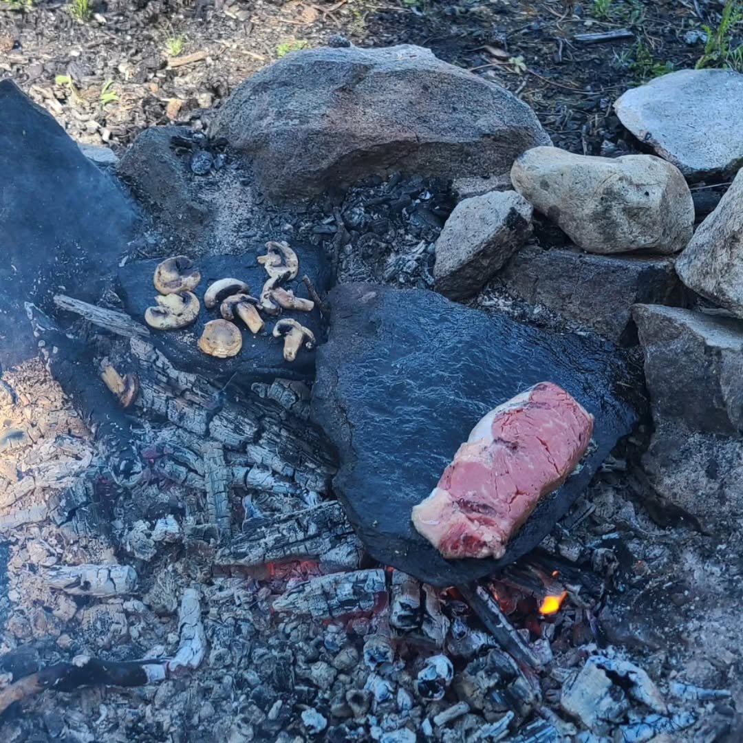 meat and mushrooms roasting on stone